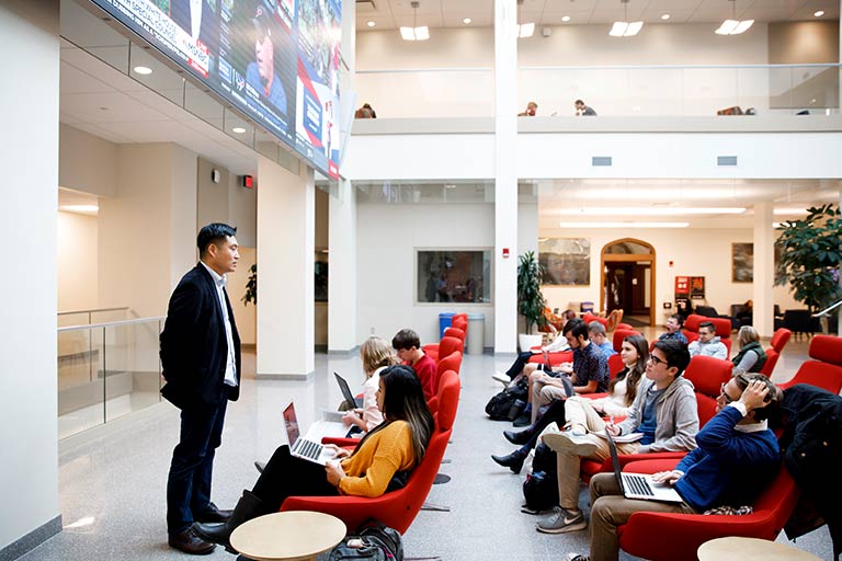 Students take notes on their laptops and listen to a speaker in the central commons, Franklin Hall.