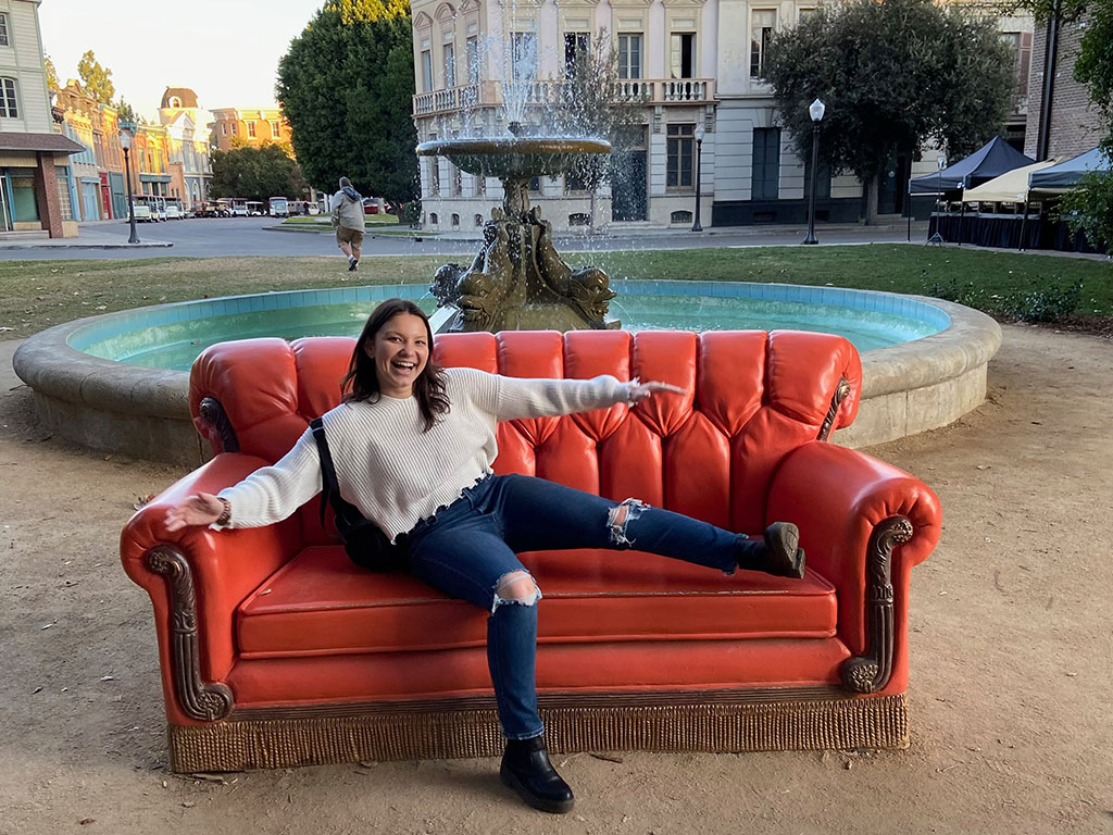 A student sitting on the 'Friends' couch at Warner Bros. Studios.