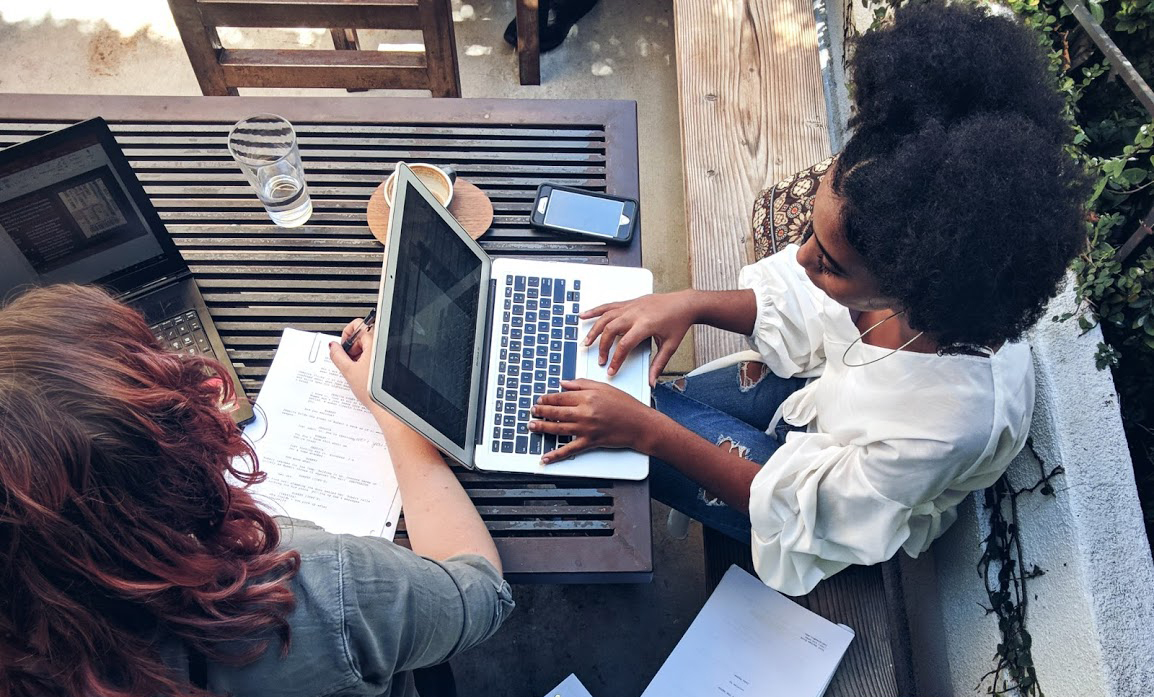 Overhead view of two student as they work on homework on their laptops.