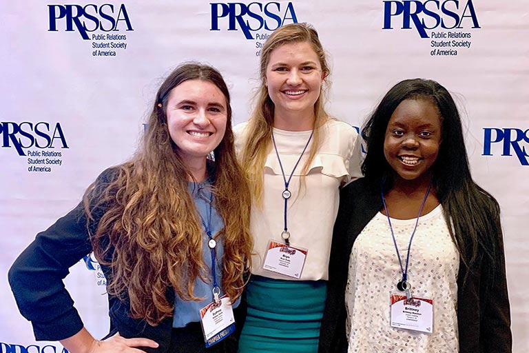 Three students pose while at an Public Relations Student Society of America event.