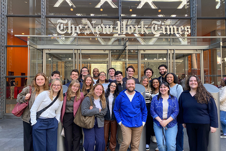 A group of people stand in front of the New York Times building.