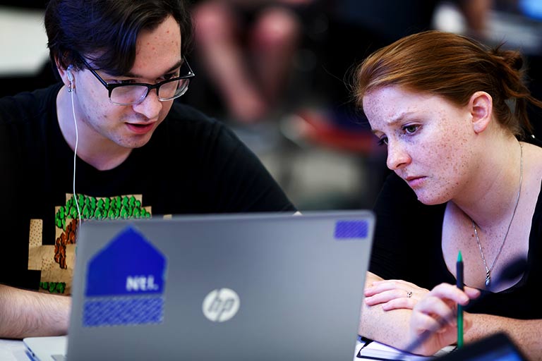 Two students work together on a laptop.