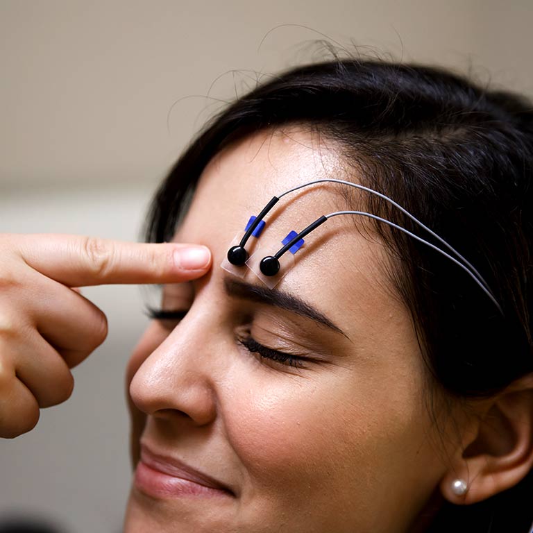A researcher's hands putting electrodes on a participant's head
